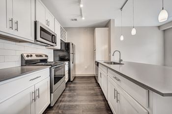 An empty kitchen with white cabinets and stainless steel appliances